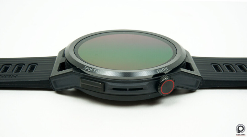 A gomb és a kattintható, tekerhető korona, közöttük a hangszóró és a mikrofon nyílása.