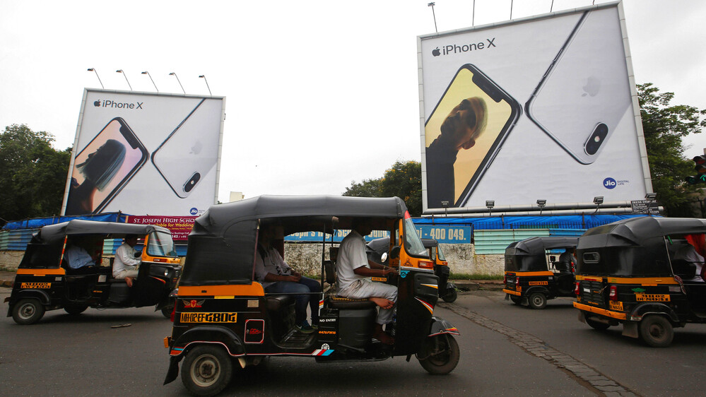 Motoros riksák Mumbaiban az iPhone X plakátjai előtt 2019-ben.