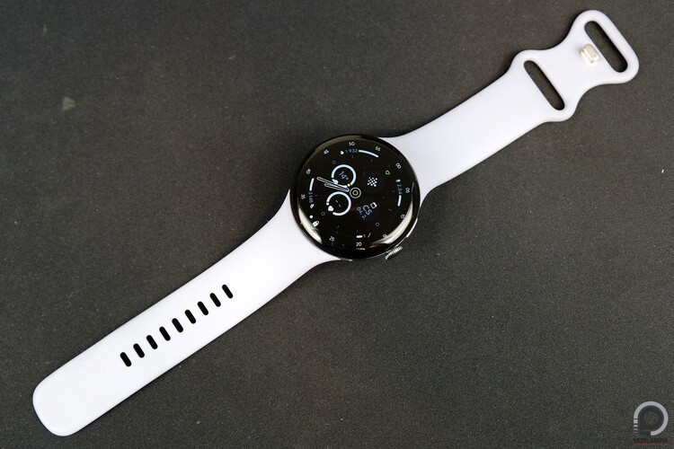 Google Pixel Watch 4 kiterítve a gyári szilikon sportszíjjal